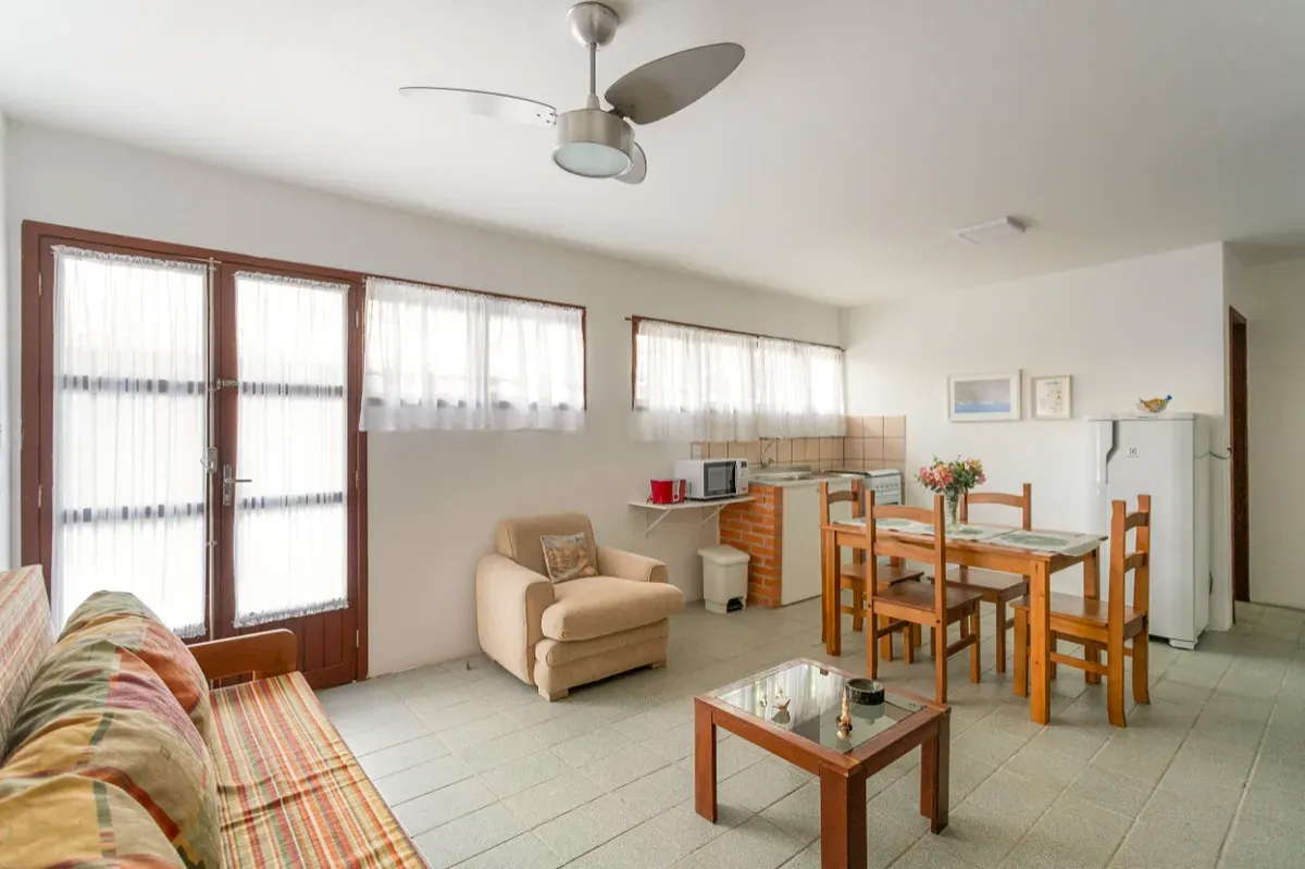 Sala ampla com sofá, poltrona, mesa de jantar e cozinha integrada ao fundo