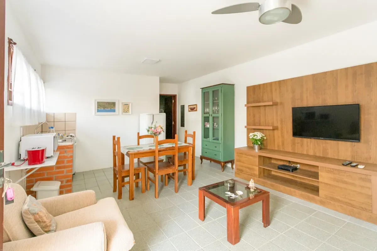 Sala com painel de madeira, TV, mesa de jantar e cristaleira verde