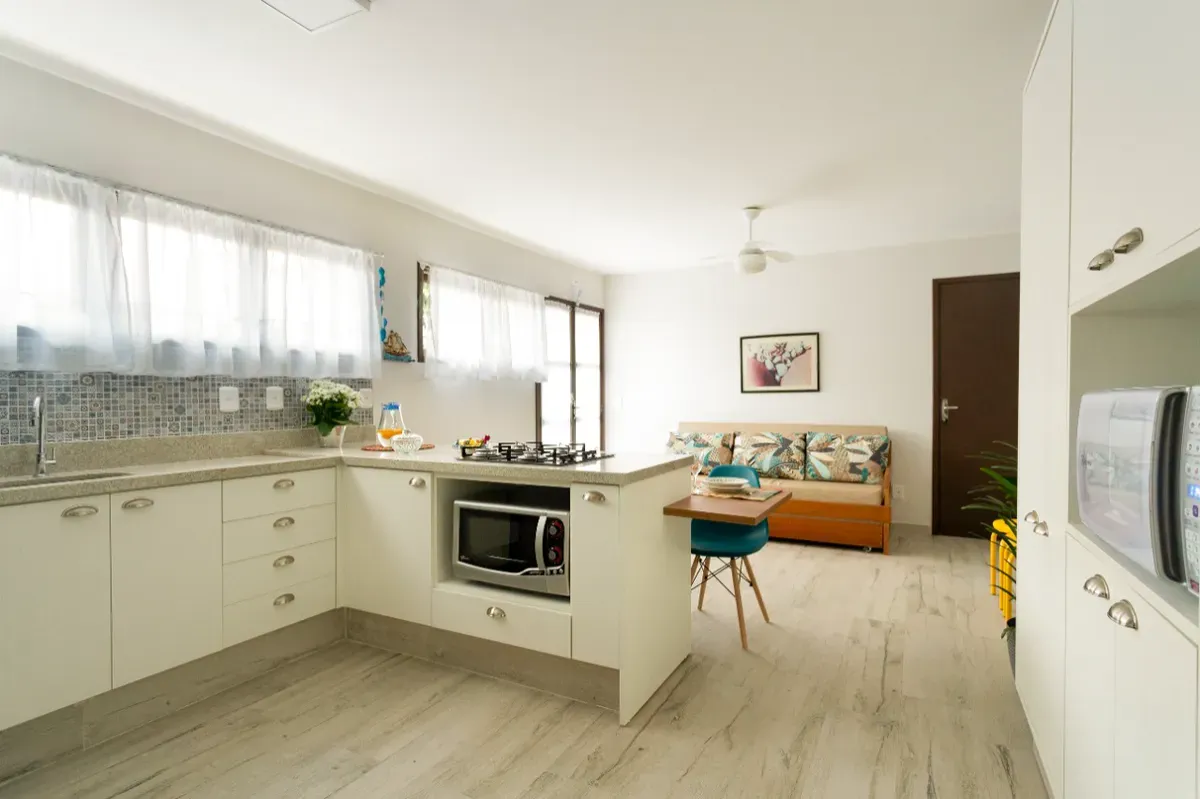 Cozinha planejada com fogão, micro-ondas e armários brancos