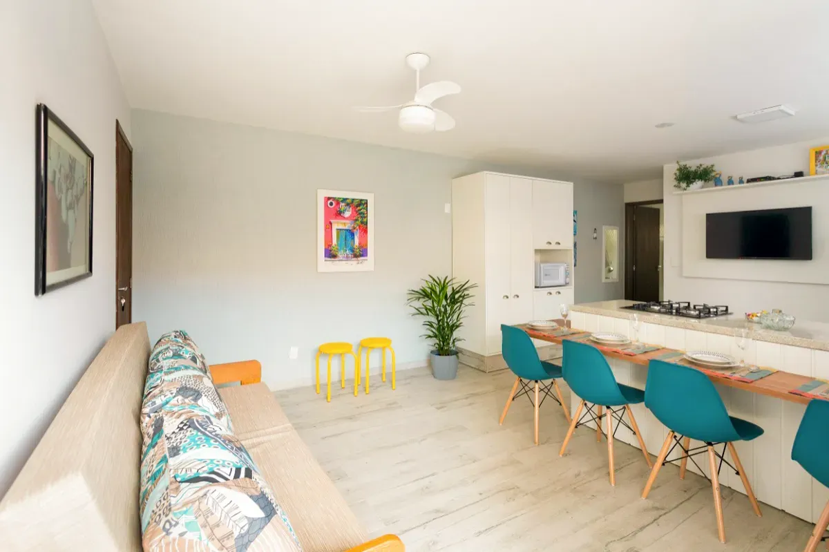 Sala clara com sofá estampado e balcão com cadeiras azul-petróleo