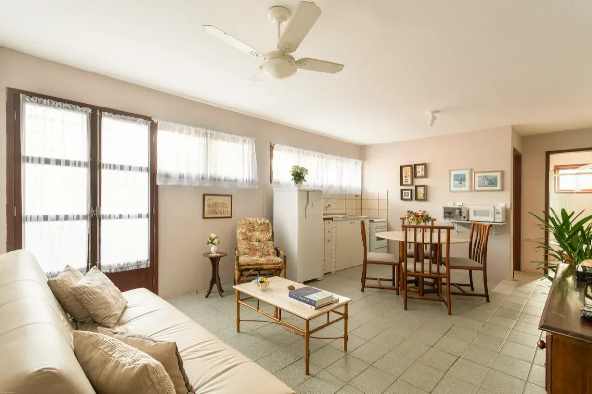 Sala com sofá, mesa de centro e mesa de jantar perto das janelas