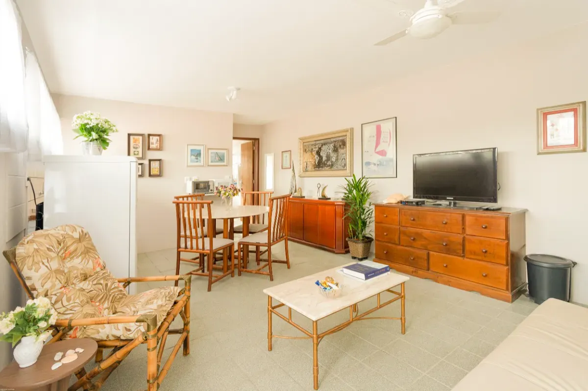 Sala com poltrona de vime, TV e cômoda de madeira