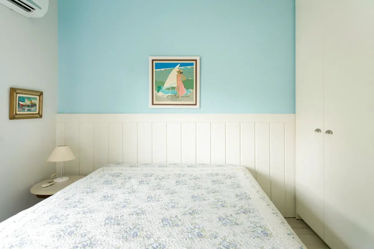 Cama de casal com quadro de veleiro na parede azul