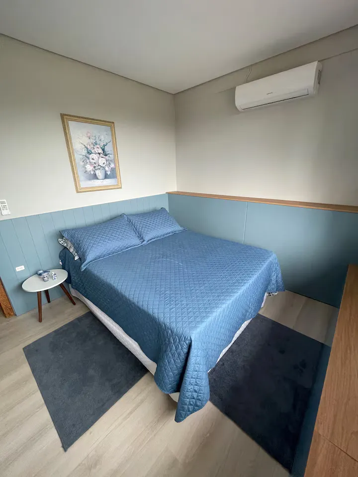 Quarto de casal em tons de azul com ar-condicionado