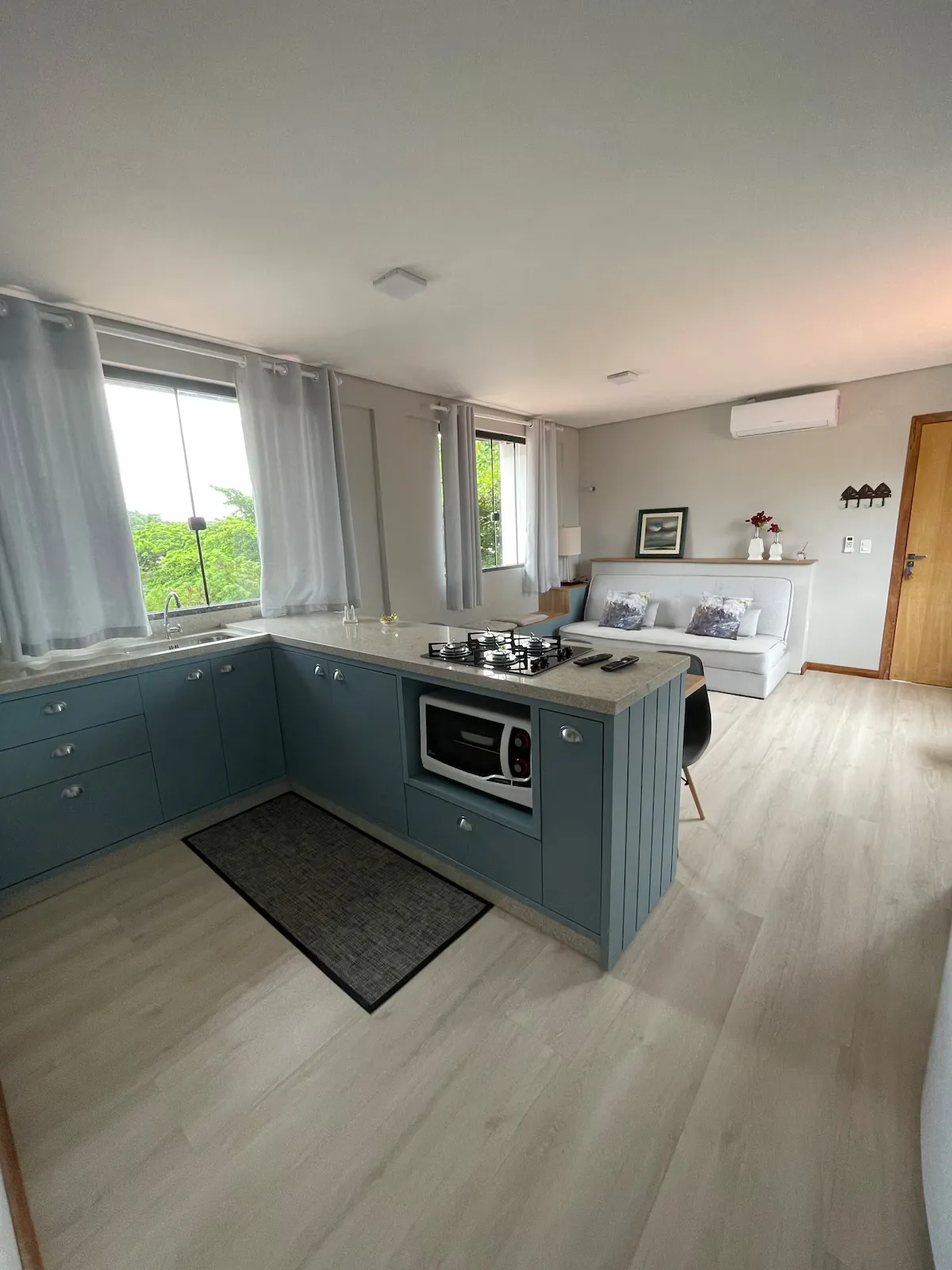 Cozinha em azul com sala e sofá-cama ao fundo