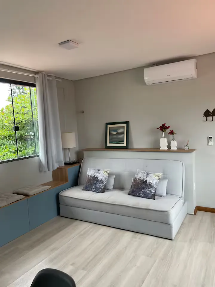 Sala com sofá-cama e janela para o verde