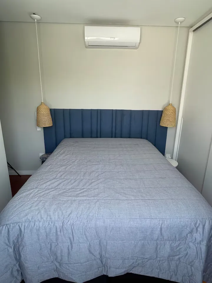 Quarto de casal com cabeceira azul e ar-condicionado