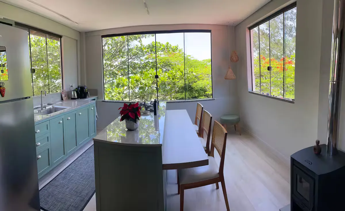 Cozinha e mesa de jantar com janelas para o verde
