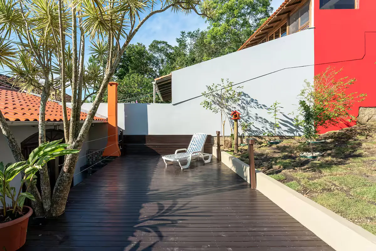 Deck de madeira com espreguiçadeira, cercado de plantas