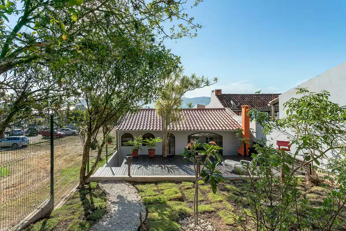 Casa vista do jardim, com árvores e caminho de pedras