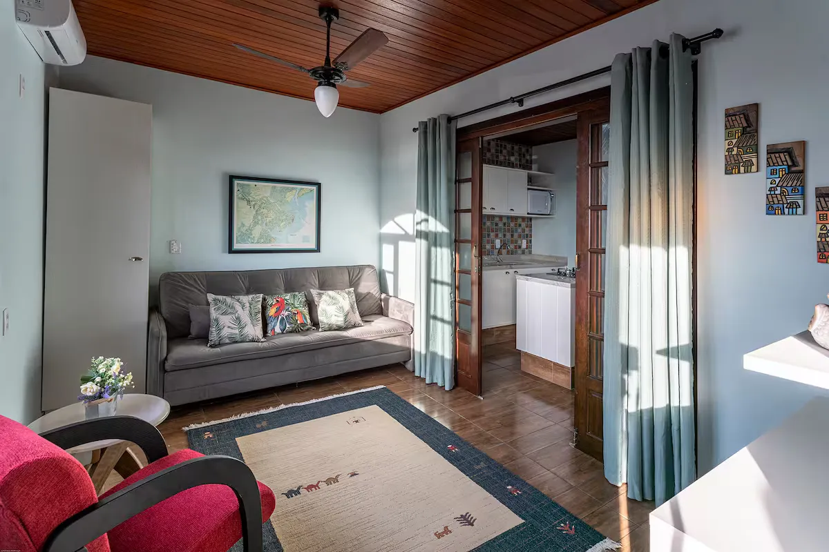 Sala com sofá, poltrona vermelha e teto de madeira