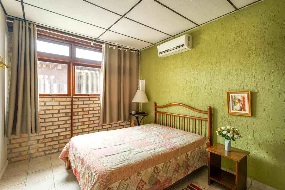 Quarto de casal com parede verde e ar-condicionado